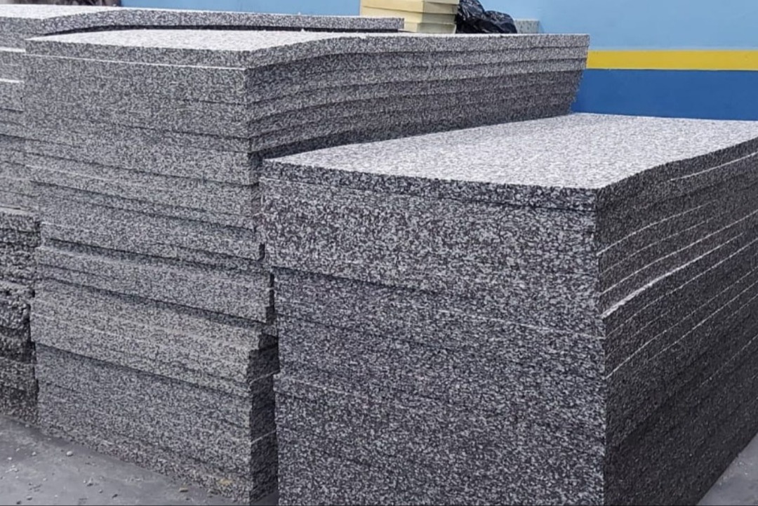 Placas de aglomerado de espuma de poliuretano empilhadas no pátio da fábrica, demonstrando capacidade produtiva sob medida